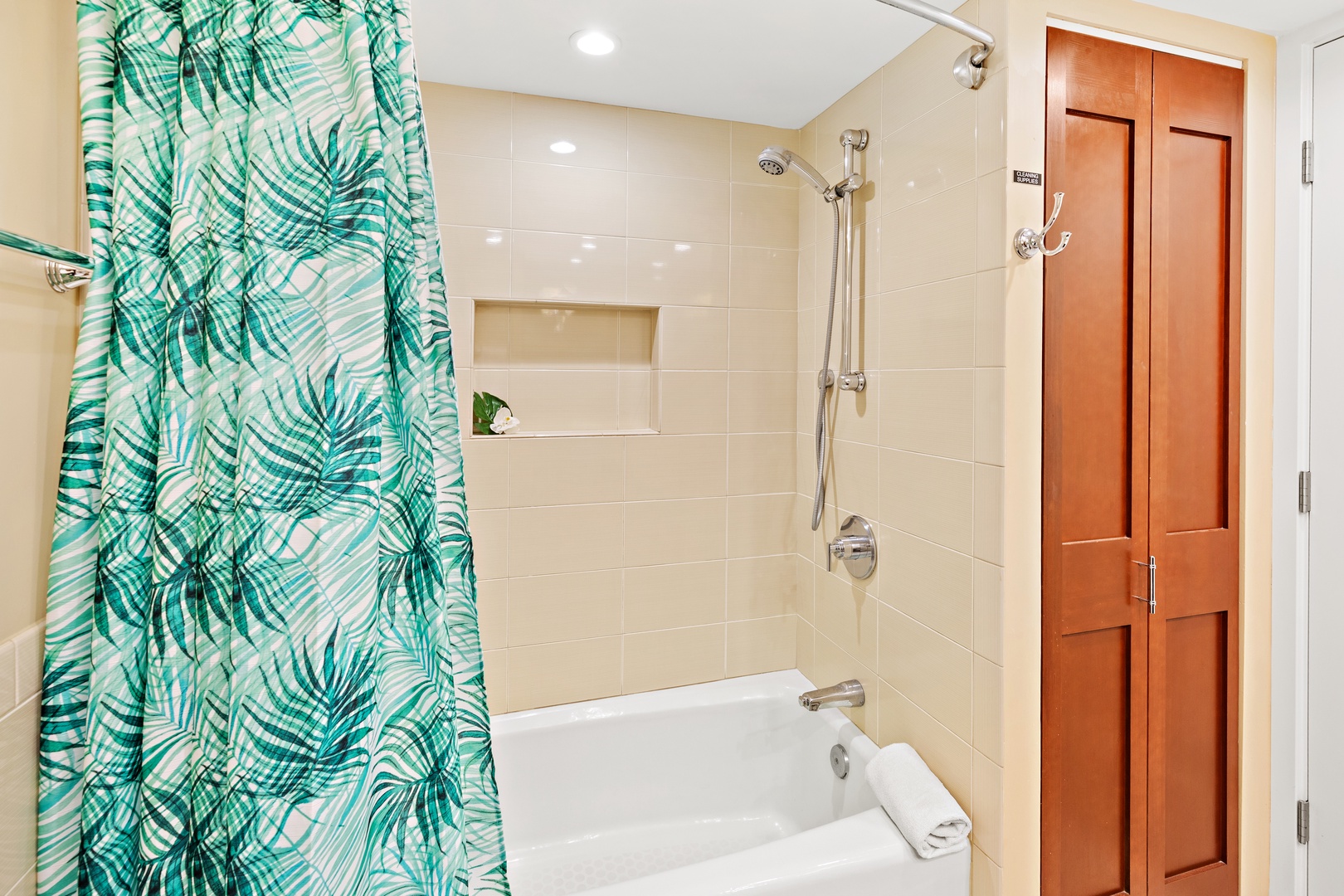 Step into your bright, tiled bathroom with a deep soaking tub and rainfall showerhead. The tropical-print curtain adds a cheerful splash of color to your daily routine.