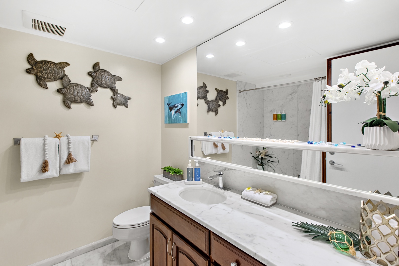 Refresh in your beautifully appointed bathroom featuring sea turtle art, marble counters, and thoughtful amenities for your comfort.