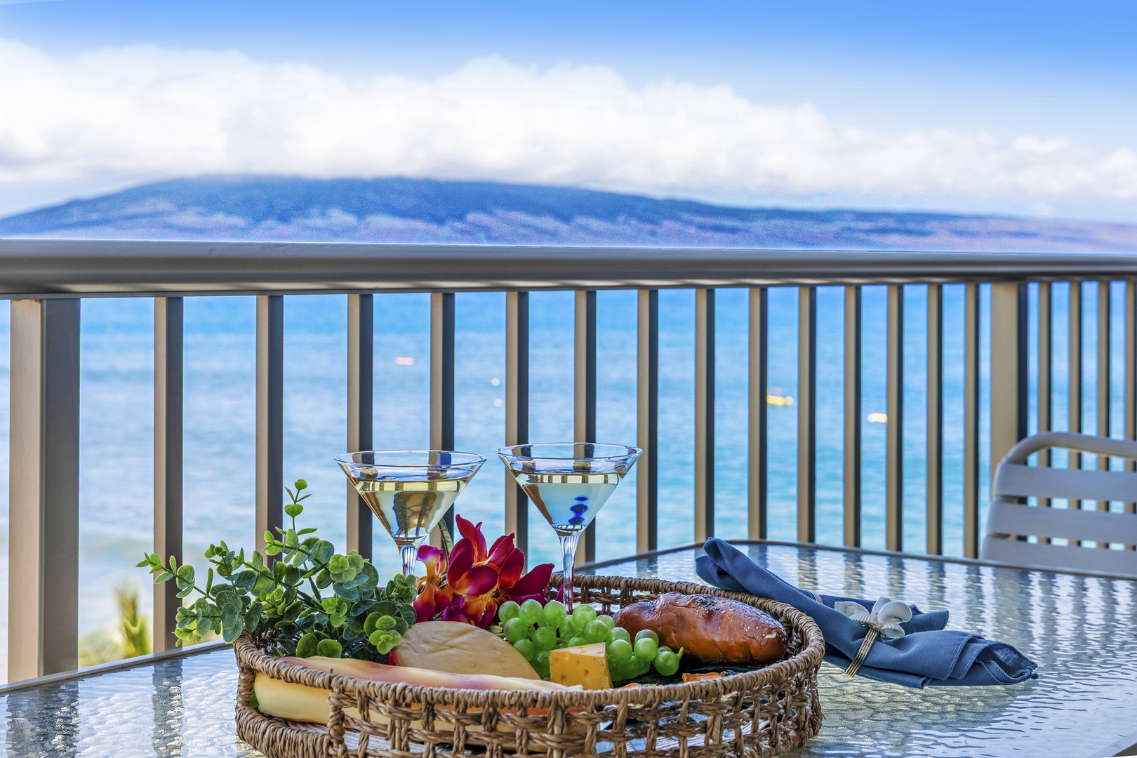 Ocean views and majestic mountain backdrop frame this inviting balcony retreat where drinks and fresh island flavors await your arrival.