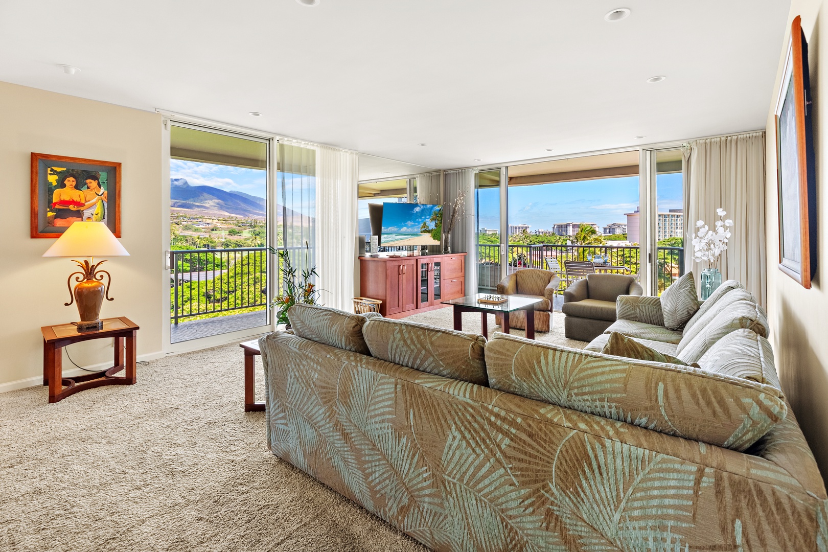 Step into your spacious living room, where tropical breezes flow through sliding doors and sweeping mountain and ocean views frame your island retreat, perfect for unwinding after a day of adventure.