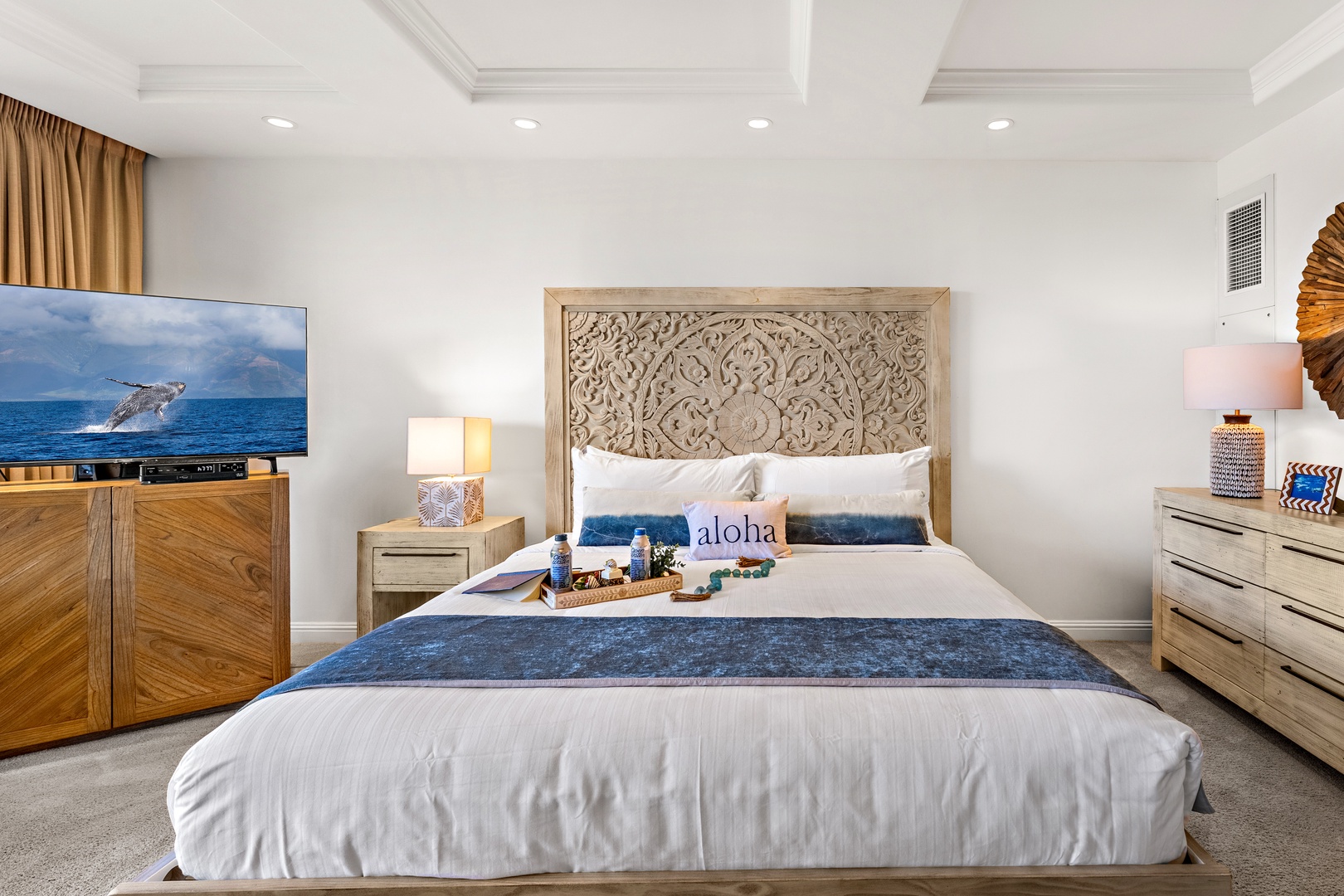 Sink into plush white linens beneath a stunning carved headboard. Your spacious bedroom features coastal-inspired décor, calming blue accents, and a large TV perfect for unwinding after beach adventures.