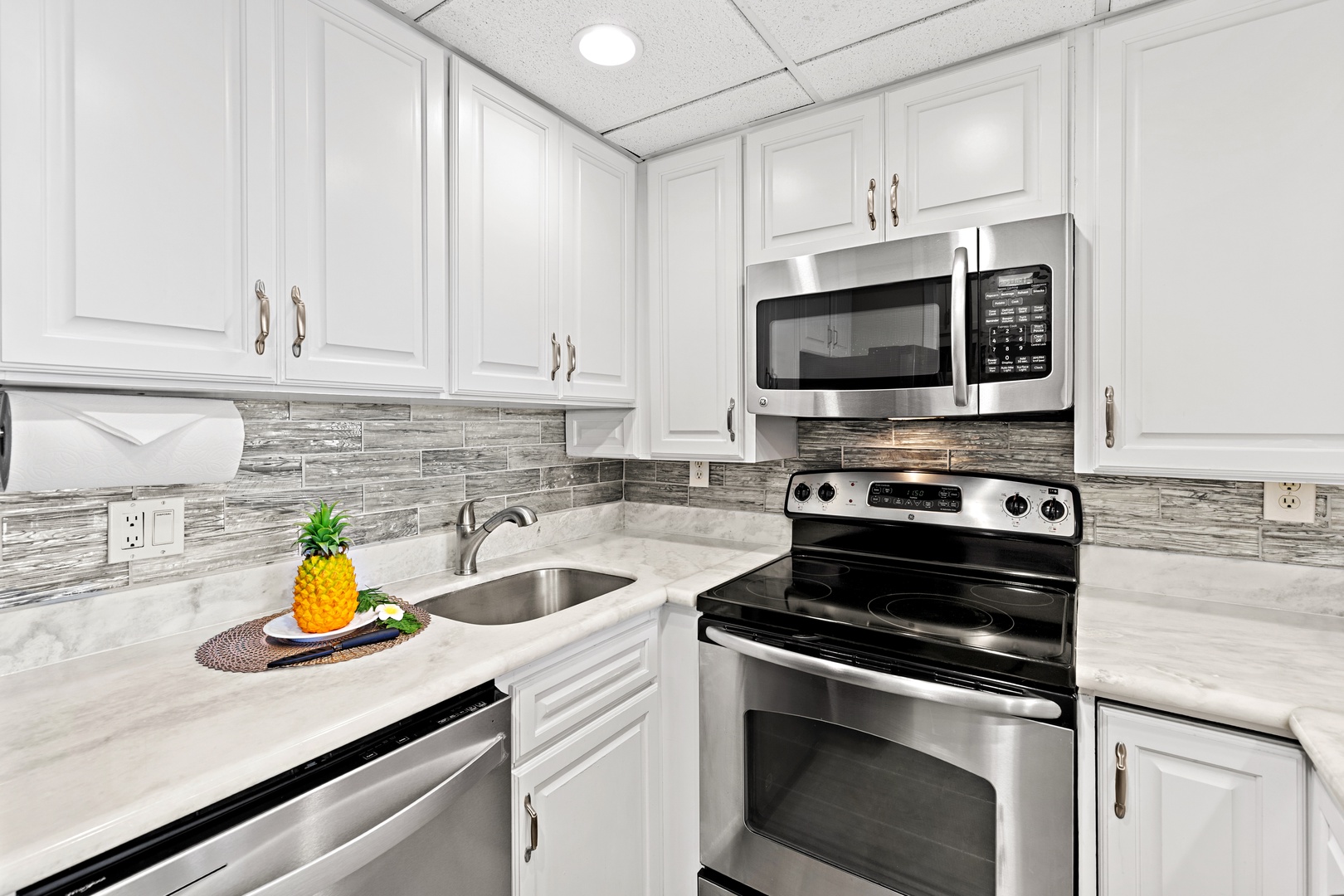 Your fully-equipped kitchen features sleek stainless-steel appliances, marble countertops, and modern gray tile backsplash—perfect for preparing meals at home during your stay.