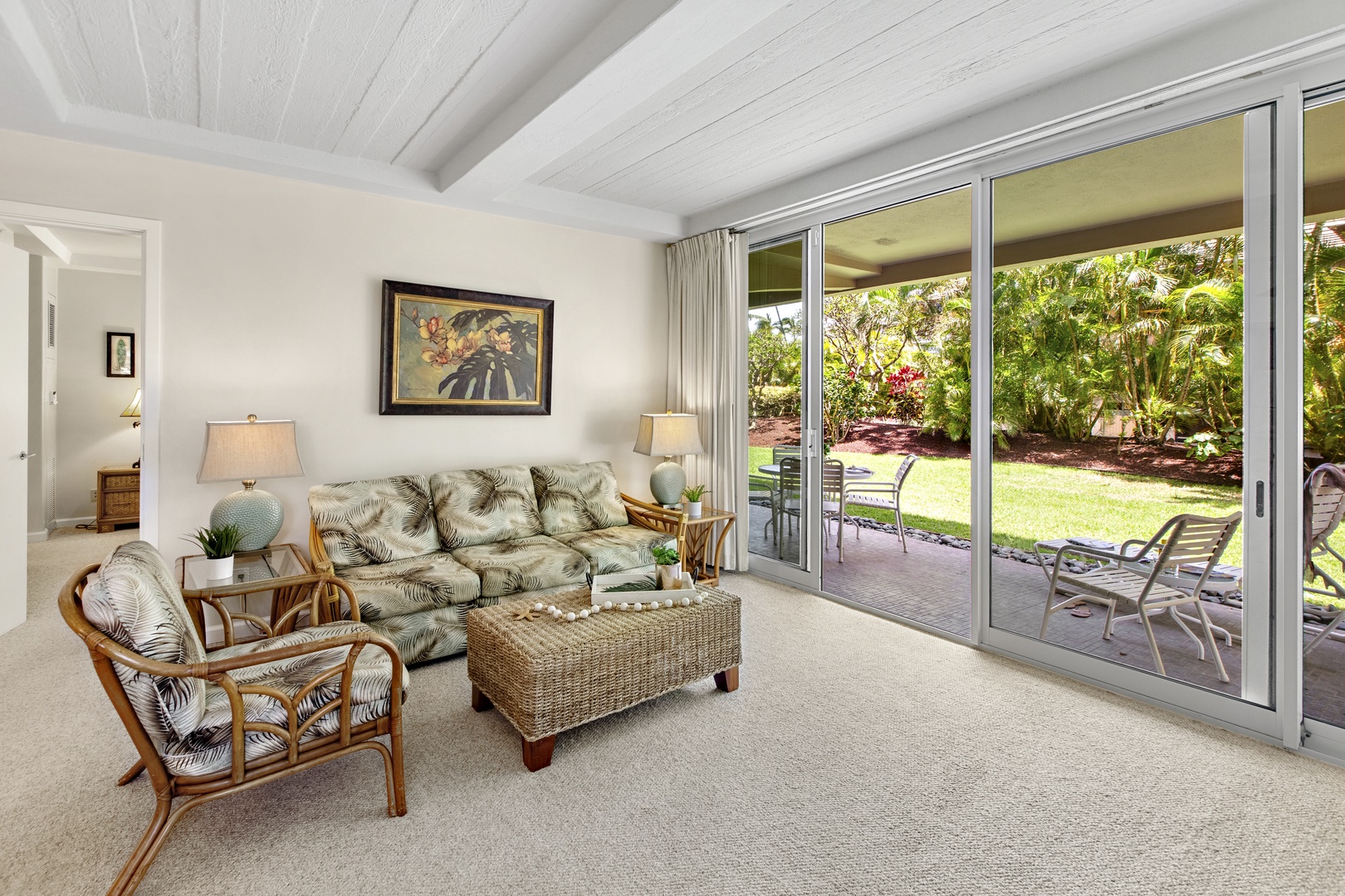 Unwind in your bright living room where tropical-print furnishings and expansive glass doors create seamless indoor-outdoor flow to your private patio.