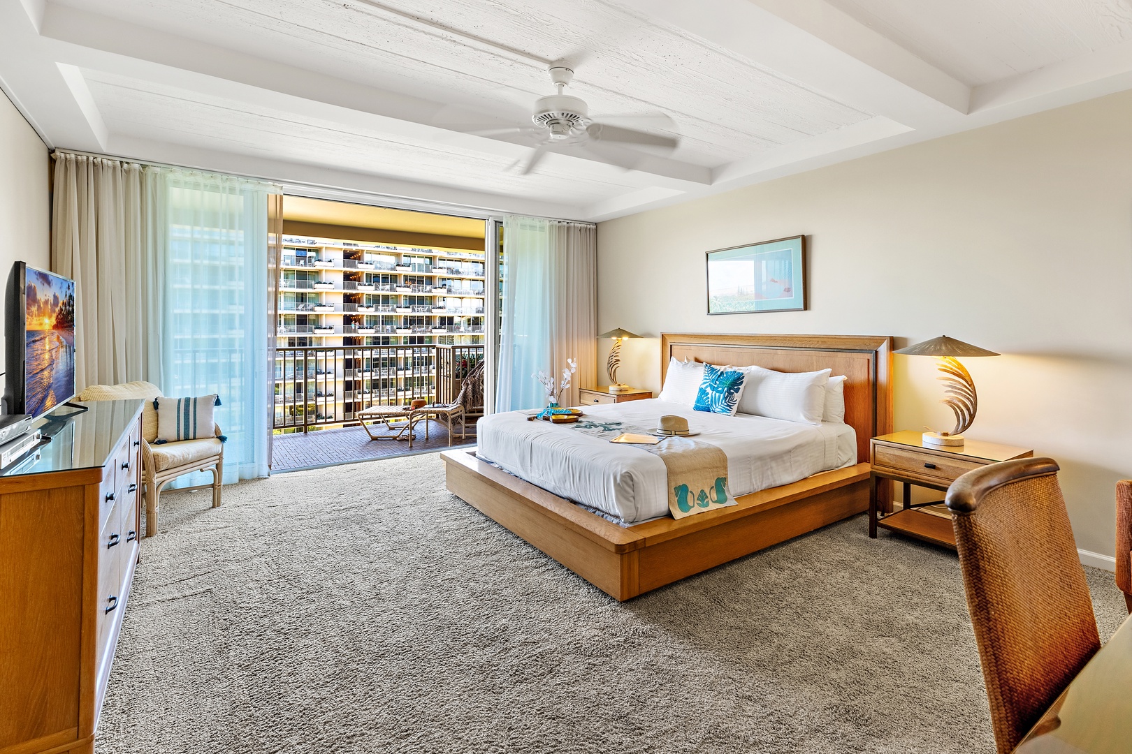 Unwind in your spacious retreat with a plush king bed, ceiling fan, and private balcony. Natural light pours in through floor-to-ceiling windows, while warm wood tones and coastal touches create your perfect escape.