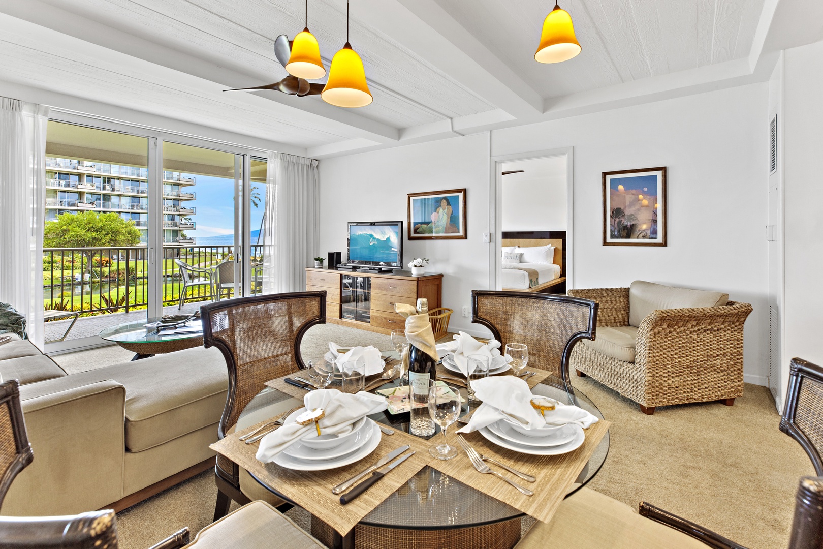 Relax in your stylish living space with warm pendant lighting and natural wicker furnishings that create a perfect coastal retreat atmosphere.