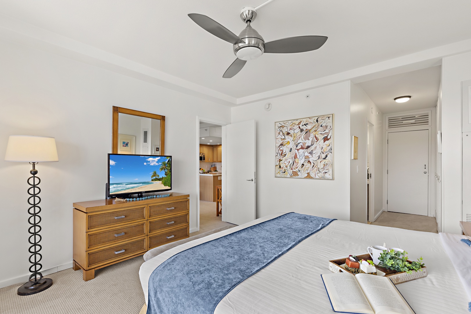 Unwind in your serene bedroom, where modern comfort meets coastal style. Your plush bed invites relaxation beneath a gentle ceiling fan, while the dresser and flatscreen offer easy convenience after a day of adventure.