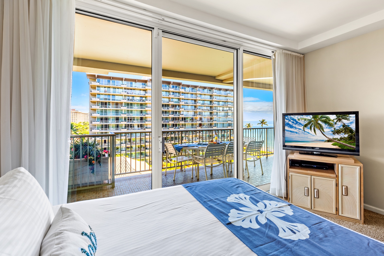 Wake up to views of nearby buildings and tropical greenery from your airy bedroom, where glass doors open onto your private balcony with outdoor seating—perfect for morning coffee or unwinding with the breeze.