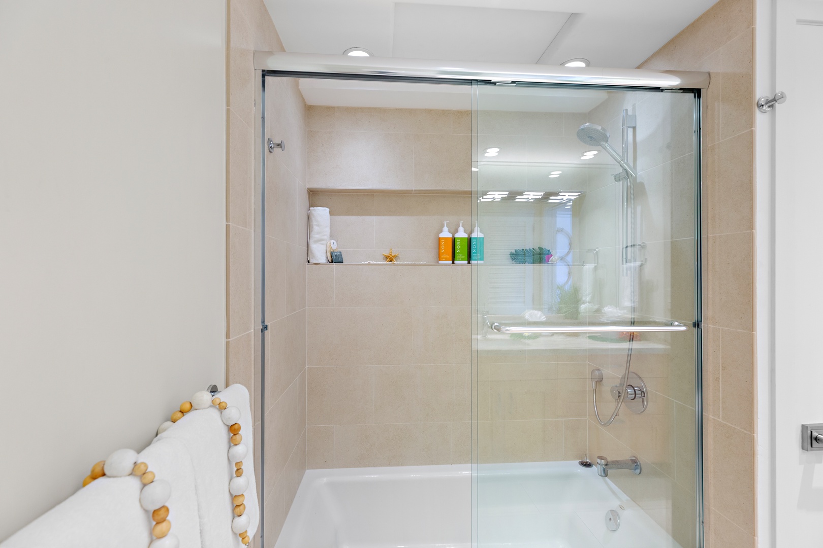 Unwind in your spacious modern bathroom, featuring a sleek tub-shower combo with glass enclosure, built-in storage niche for your toiletries, and calming neutral tones that invite relaxation.