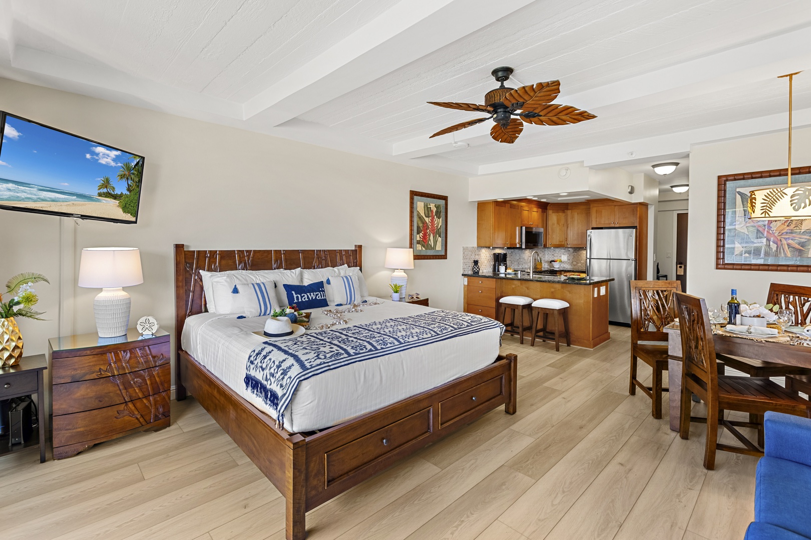 Unwind in your tropical haven with a king bed, full kitchen, and island-inspired decor beneath exposed beams and a palm leaf ceiling fan.