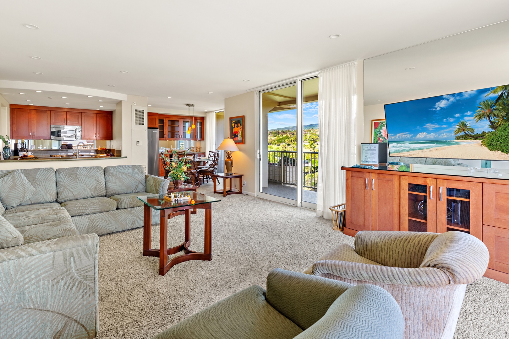 Sink into plush seating where your living room flows into a full kitchen and opens to a private balcony with lush green views—pure island ease.