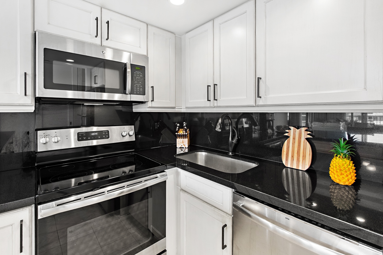 Your fully equipped kitchen boasts sleek stainless steel appliances and modern white cabinetry with striking black granite countertops—perfect for whipping up anything from quick breakfasts to elaborate dinners.