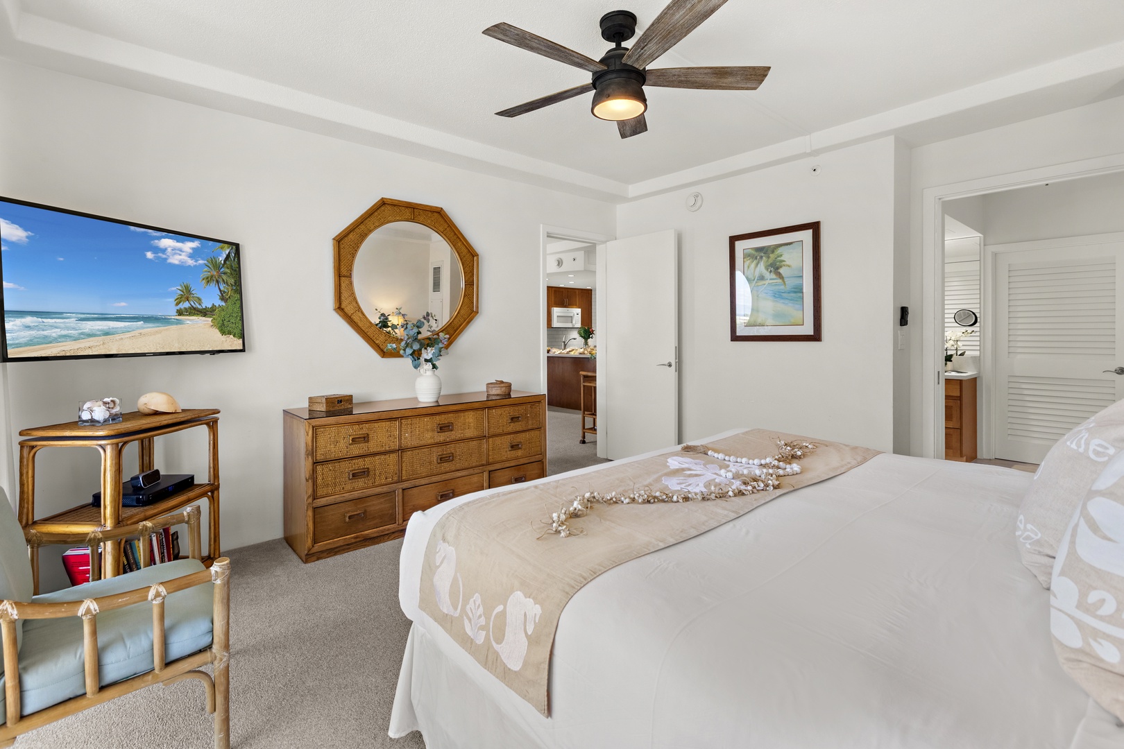 Peaceful bedroom featuring a plush bed, warm wood furnishings, and a ceiling fan for added comfort in a relaxed island setting.