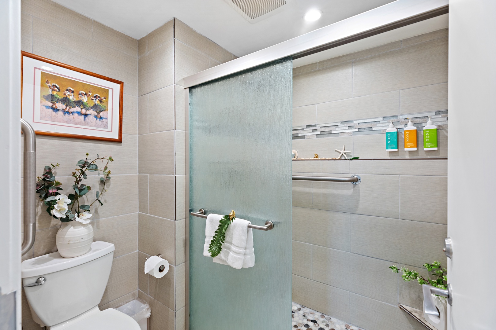 Your private bathroom features a modern walk-in shower with spa-inspired amenities, elegant tile work, and thoughtful touches like fresh greenery and coastal decor to help you unwind after a day of adventure.