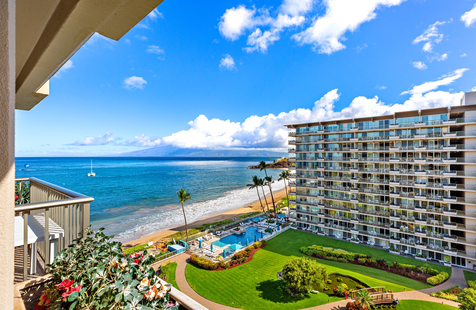 Panoramic coastal view from the property reveals a tranquil beachfront with manicured gardens, pool, and stunning ocean vistas stretching toward distant islands.