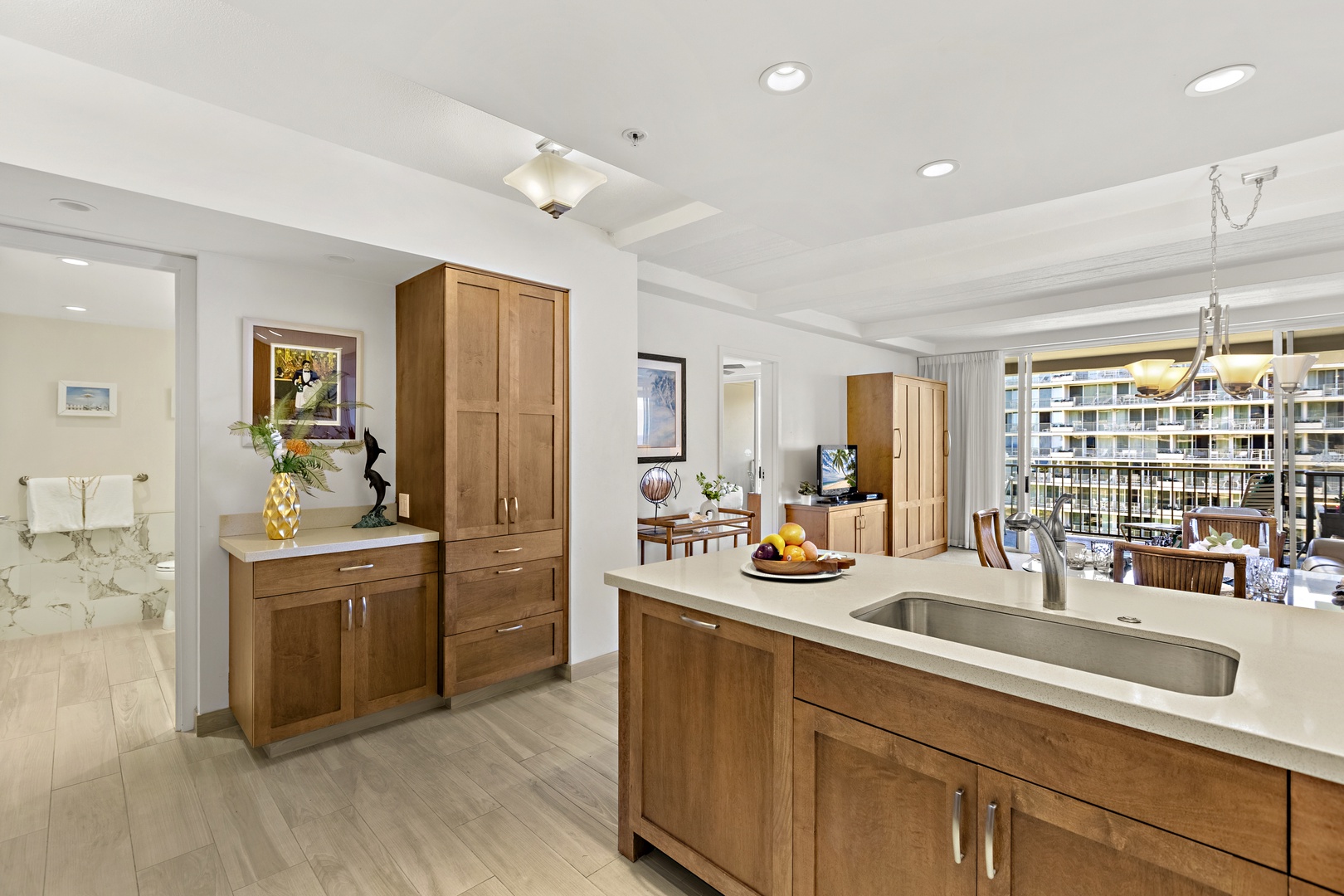 Bright, open kitchen with granite island, warm wood cabinetry, and a welcoming entry flow into the living space.