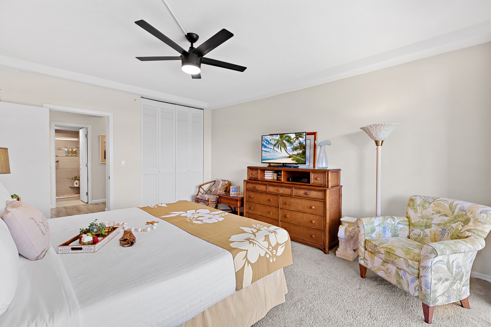 Your spacious bedroom features a plush bed, tropical accents, and a cozy sitting chair where you can relax after a day of island adventures.