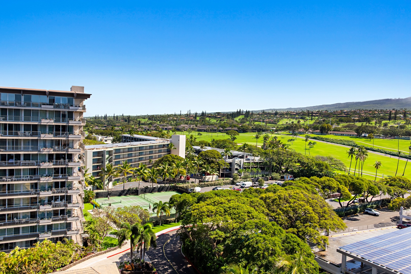 The property sits amid lush landscaping with expansive fairways and mountain vistas stretching to the horizon—a serene location for those seeking tropical relaxation and outdoor beauty.