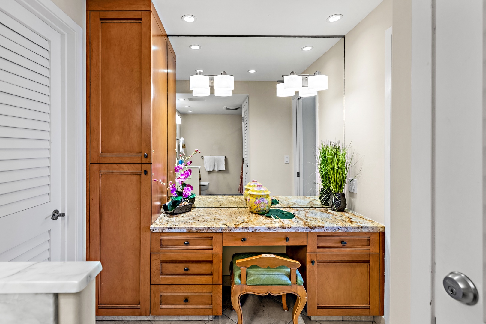 Pamper yourself at your elegant vanity with granite countertops, warm wood cabinetry, and perfect lighting for your morning routine.