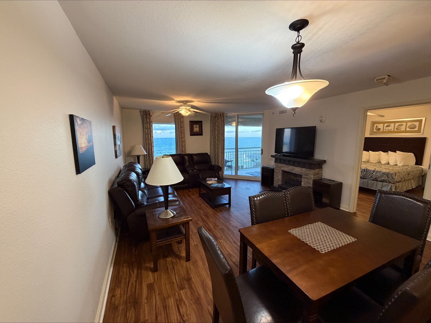 Bright open living space with leather seating, warm hardwood floors, and stunning ocean views through sliding glass doors. Perfect for gathering around the dining table or relaxing on the plush sofa.