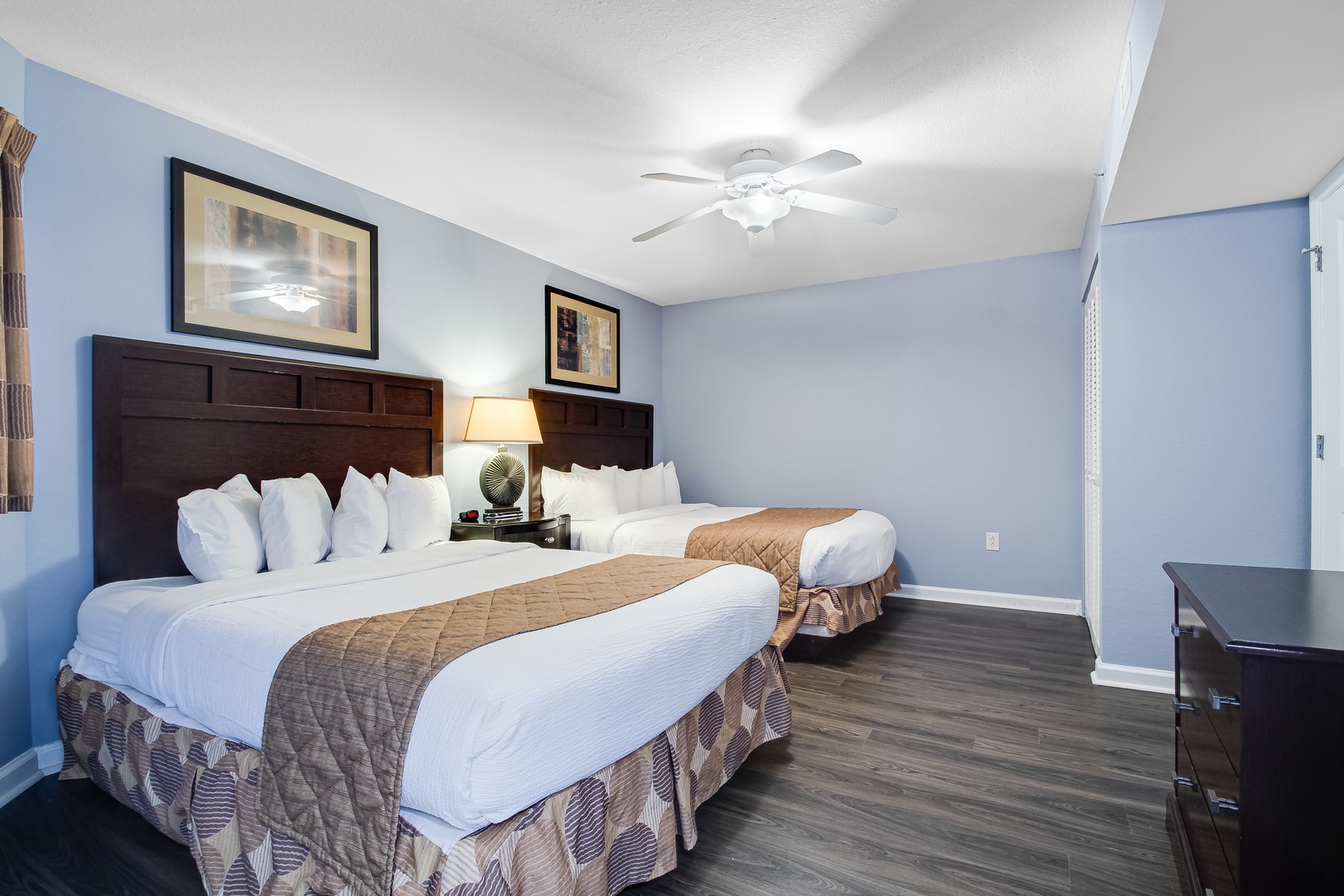 Relax in your serene bedroom featuring two plush beds with crisp linens, soothing blue walls, and warm lighting for peaceful nights.