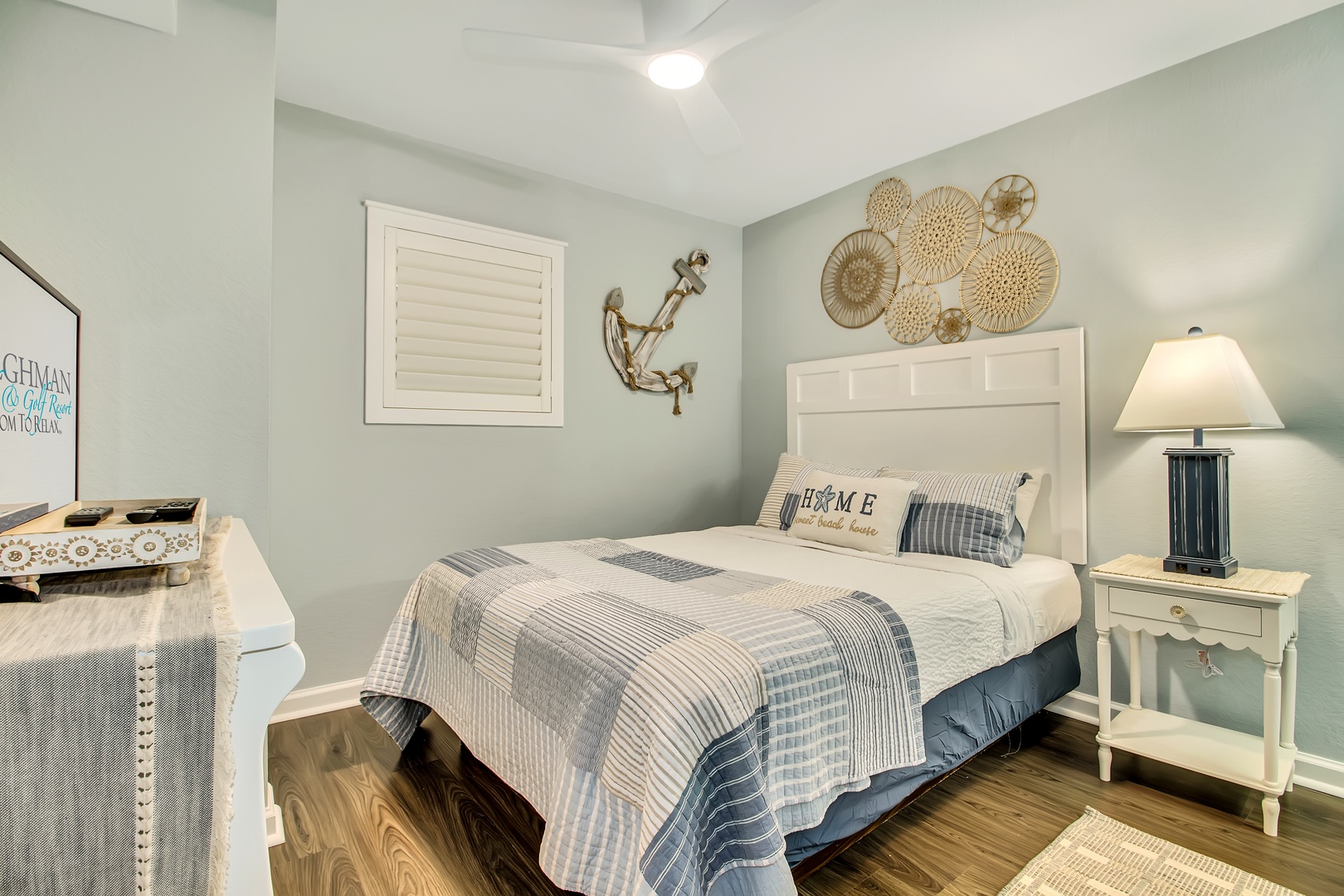 Drift off in your coastal-themed bedroom featuring soft blue and white linens, charming nautical decor, and warm bedside lighting.