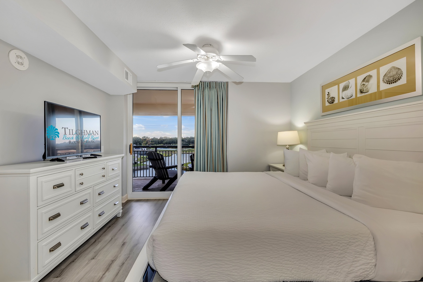 A serene bedroom with crisp white linens and coastal accents invites you to unwind. Step onto your private balcony to enjoy a peaceful waterfront view and morning coffee.