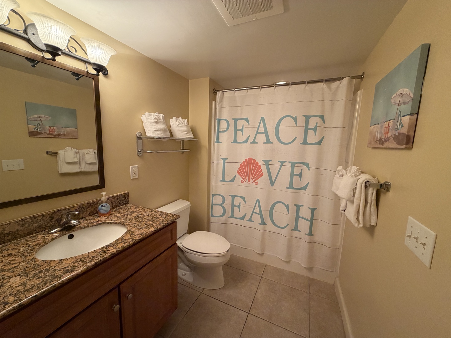 Your beach-themed bathroom offers coastal charm with a whimsical shower curtain and seaside artwork to start your mornings with a smile.