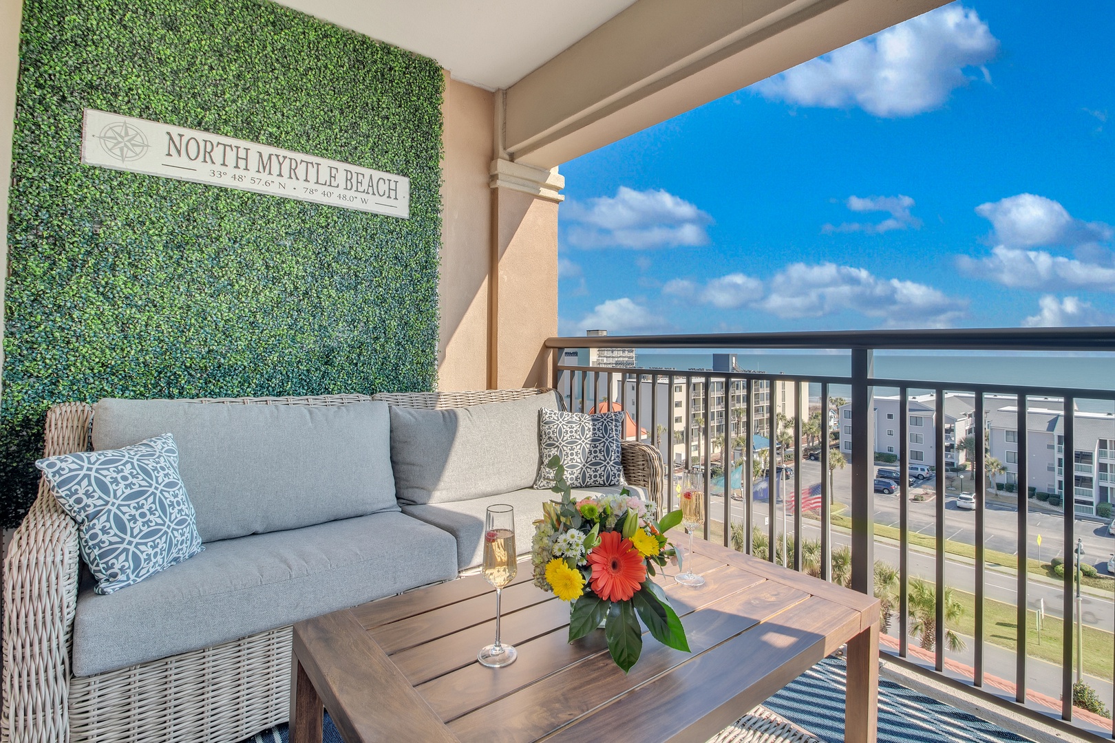 Unwind on your private balcony with comfy seating and fresh flowers, overlooking North Myrtle Beach's vibrant coastline.