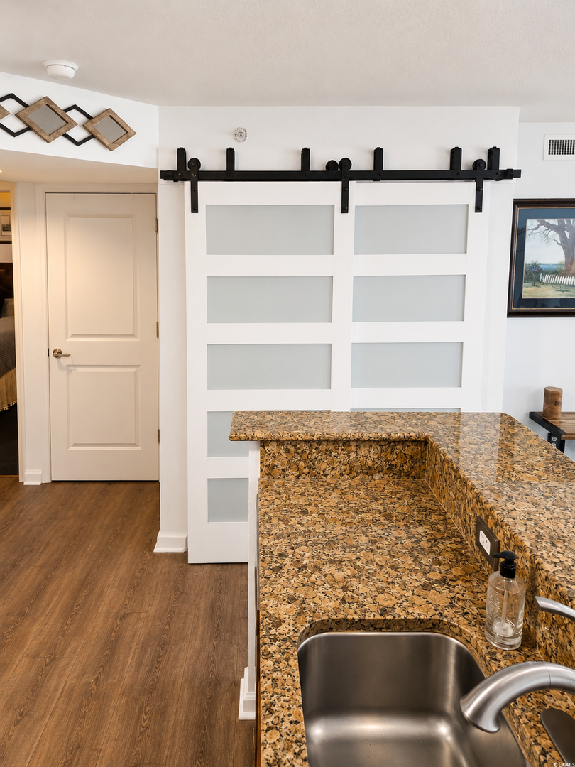 Your stylish kitchen features granite countertops, a stainless steel sink, and charming barn-style sliding doors that add character and warmth to your vacation space.