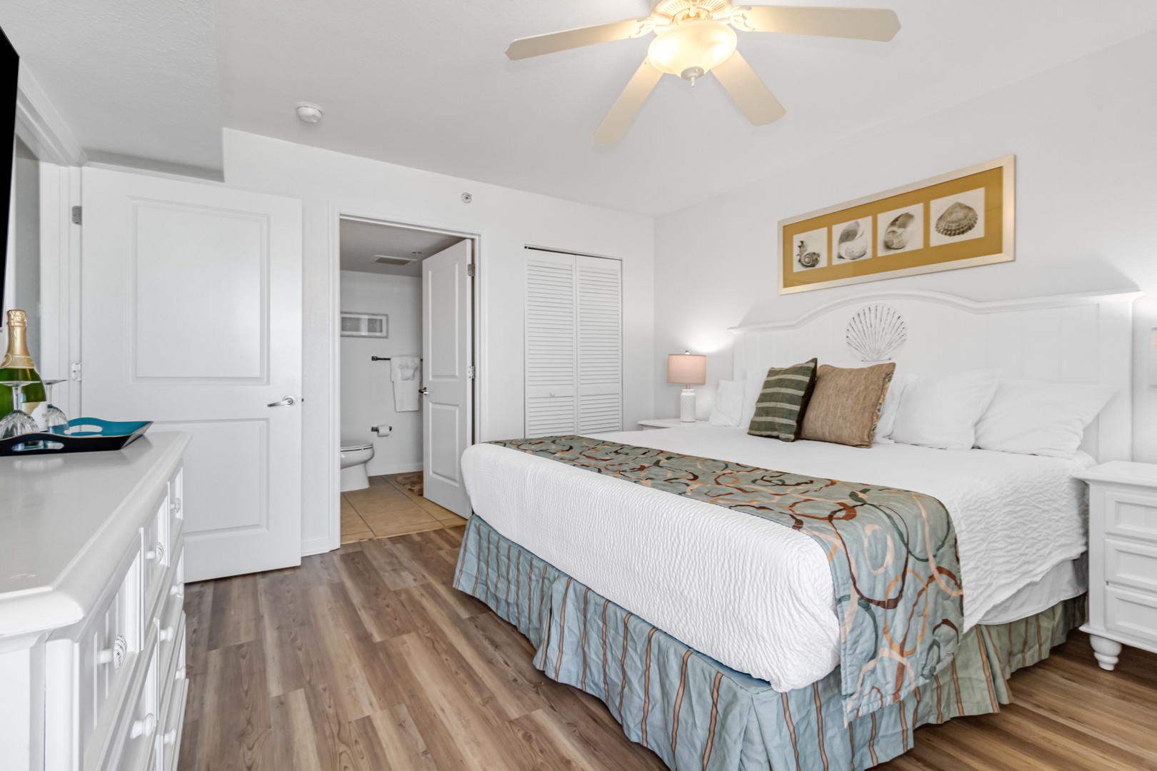 Unwind in your coastal-inspired bedroom featuring crisp white linens, ocean-themed decor, and a mini kitchenette for morning coffee.