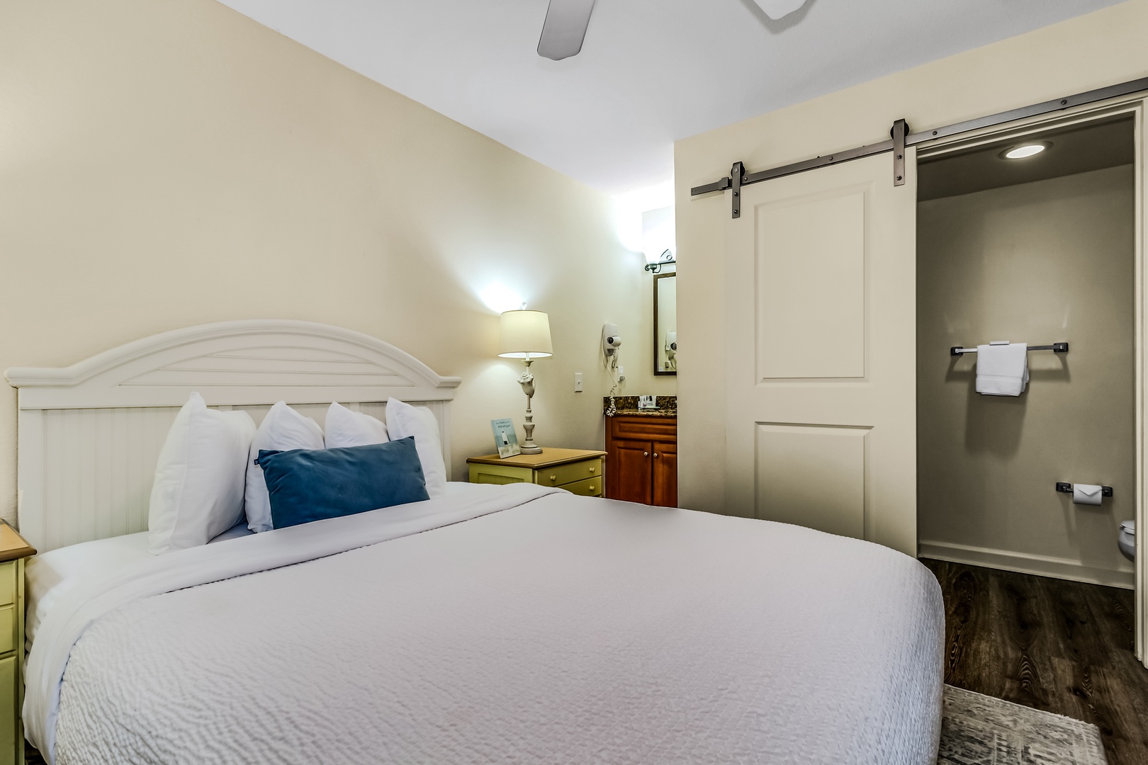 Settle into your beautifully appointed bedroom featuring crisp linens, modern amenities, and a stylish sliding barn door leading to your private bathroom.