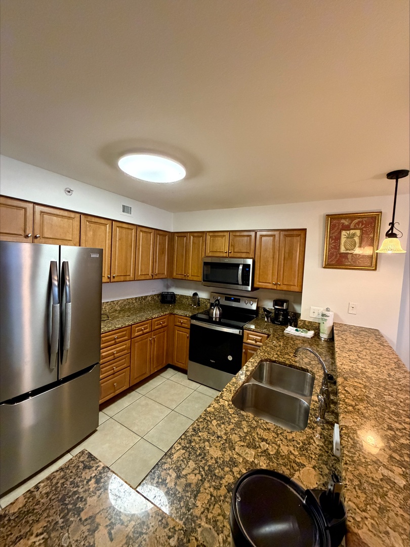 Your fully equipped kitchen features granite countertops, stainless steel appliances, and warm wood cabinetry—everything you need to prepare meals and start each morning with coffee.