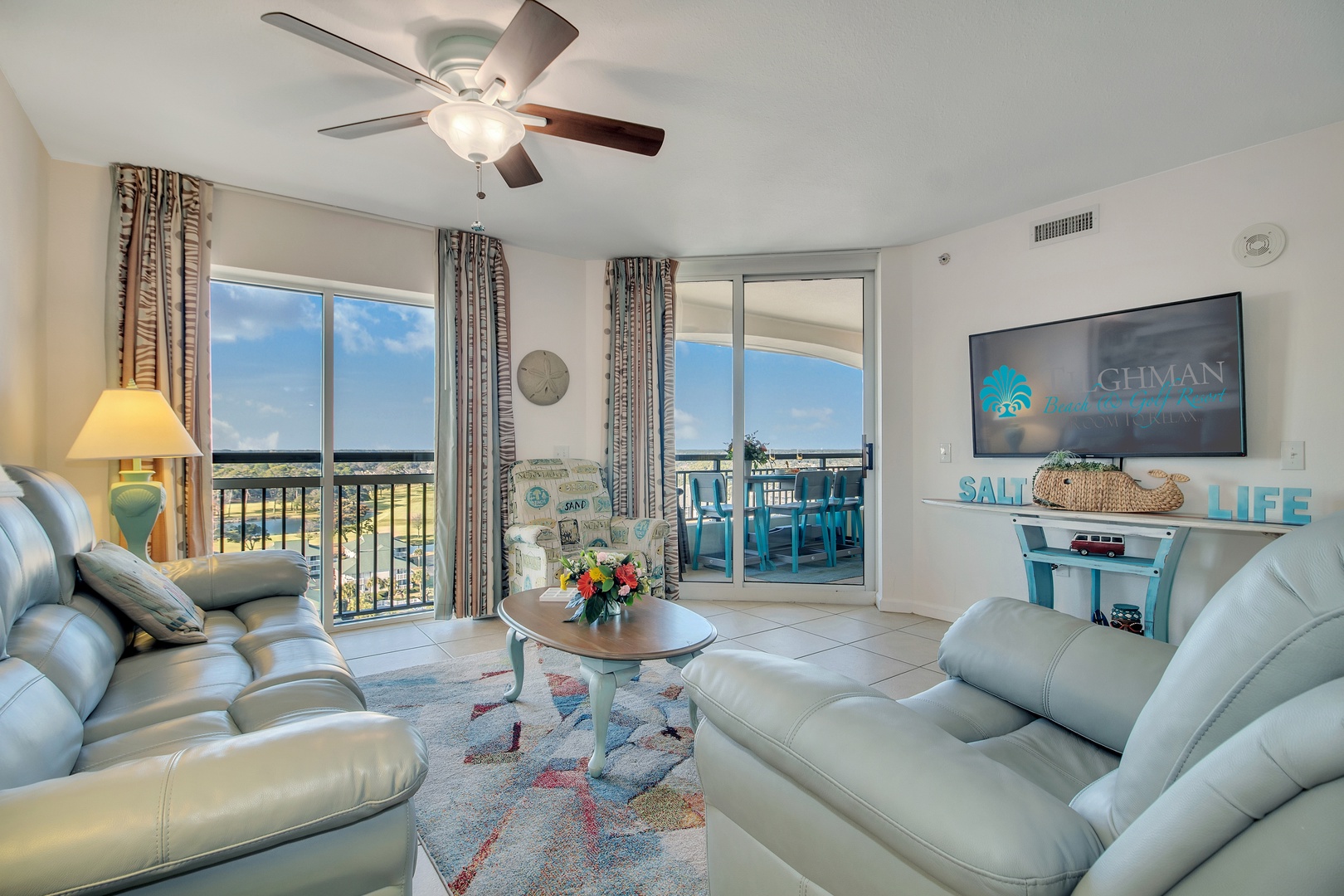 Sink into plush leather sofas while enjoying coastal views from your private balcony in this bright, airy living space.