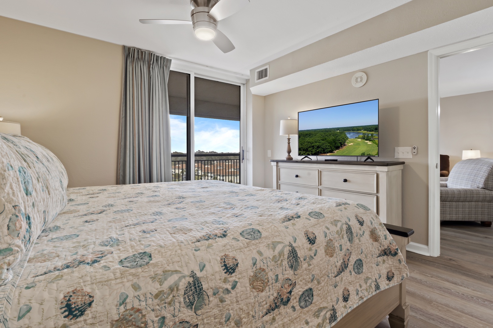 Unwind in your spacious bedroom with golf course views, featuring a comfortable bed, flatscreen TV, and private balcony access.