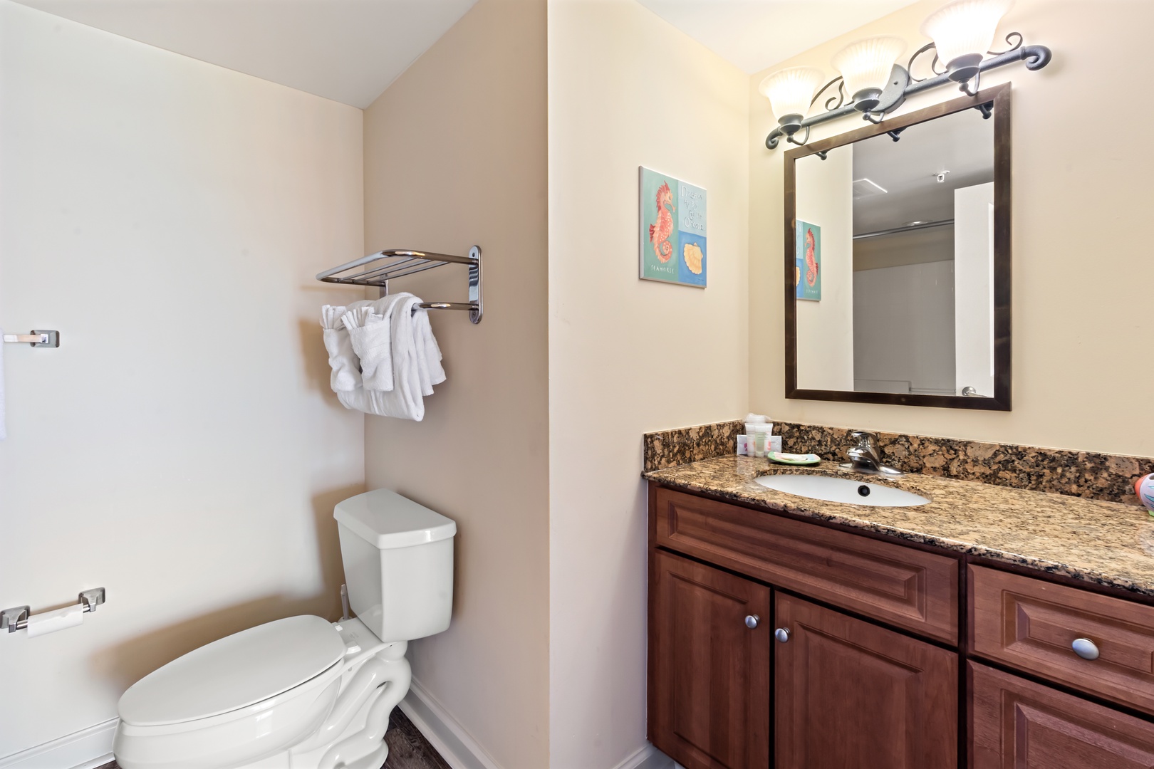 Freshen up in your elegant bathroom featuring granite countertops, warm wood cabinetry, and fluffy towels awaiting your arrival.
