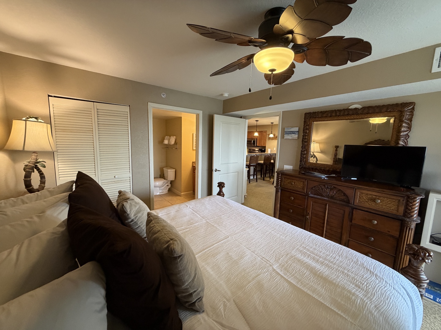 Unwind in your spacious bedroom featuring elegant furnishings, a flat-screen TV, and tropical ceiling fan for ultimate comfort.