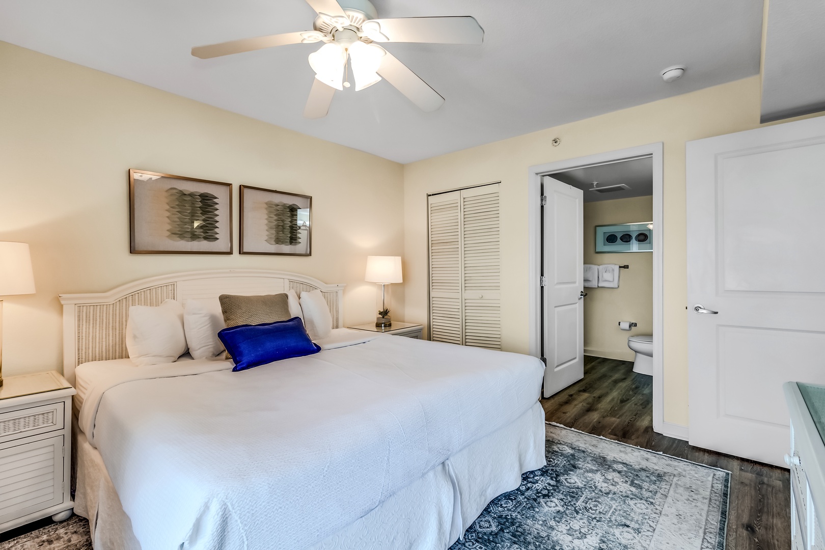 Drift into peaceful sleep in your bright, coastal-inspired bedroom with crisp linens and a gentle ceiling fan overhead.