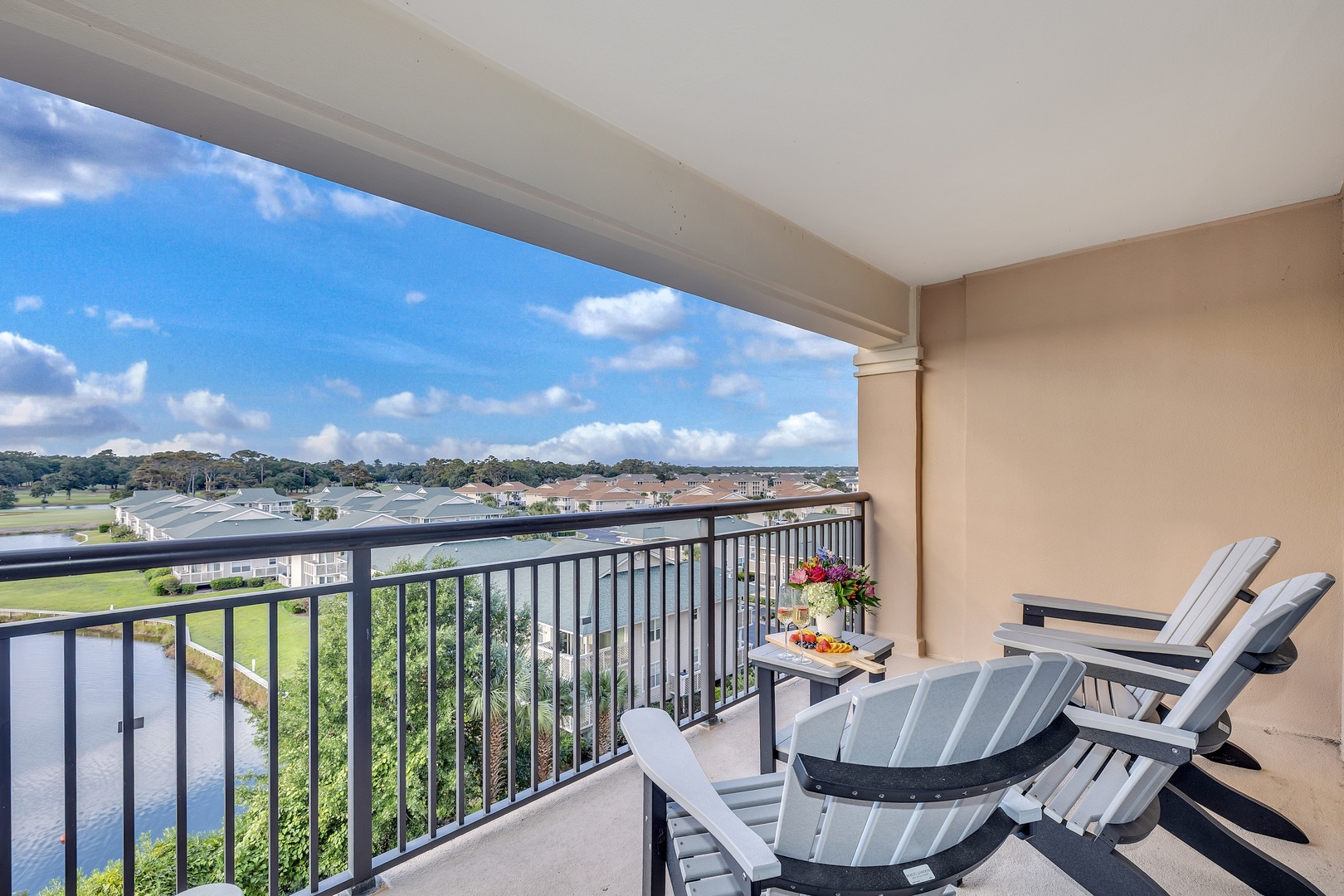 Settle into your private balcony with Adirondack seating and sweeping views of lush greenery and tranquil water below—a peaceful retreat perfect for morning coffee or sunset unwinding.