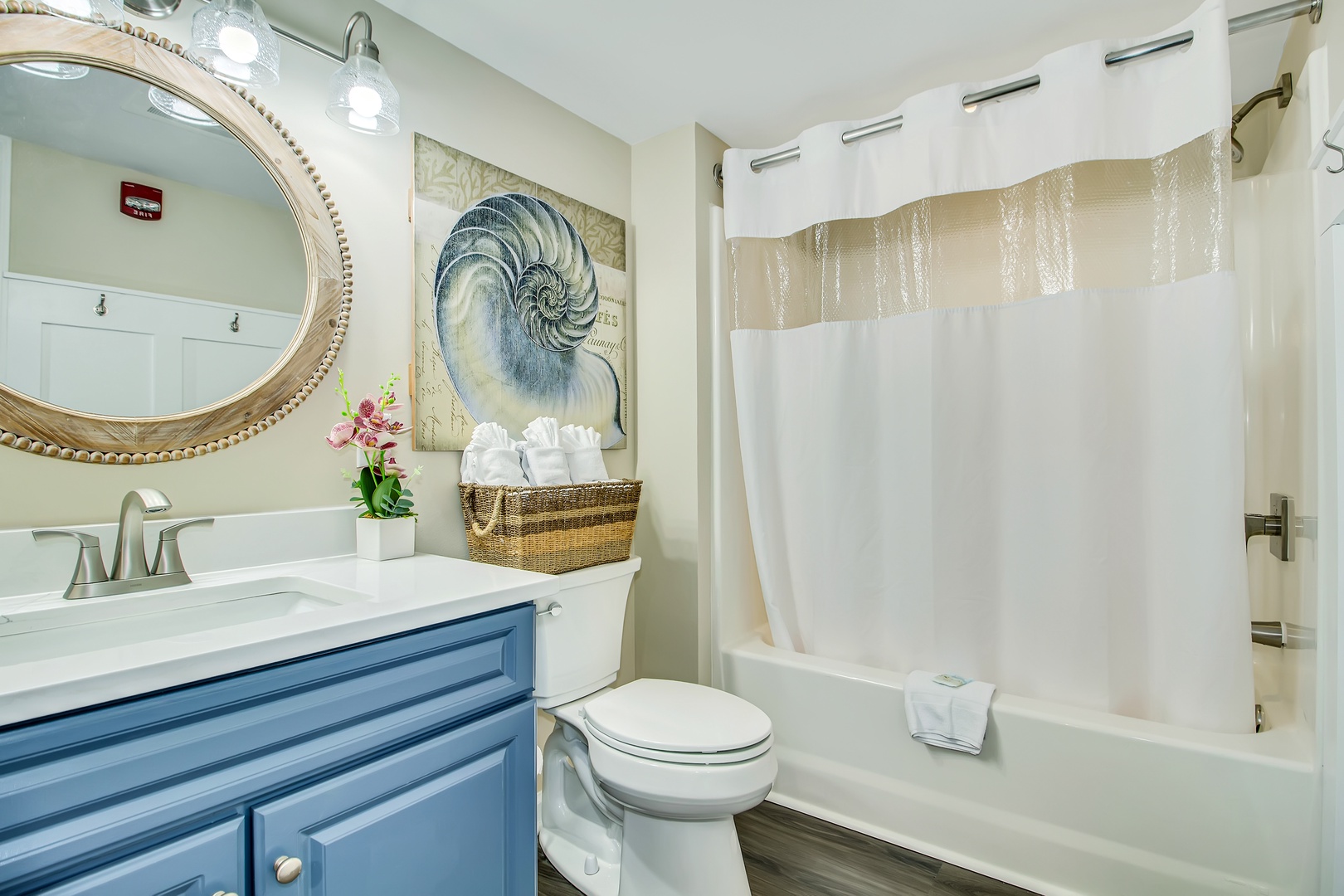 Step into your beautifully appointed bathroom with coastal charm, featuring a luxurious tub-shower combo and elegant nautilus artwork.