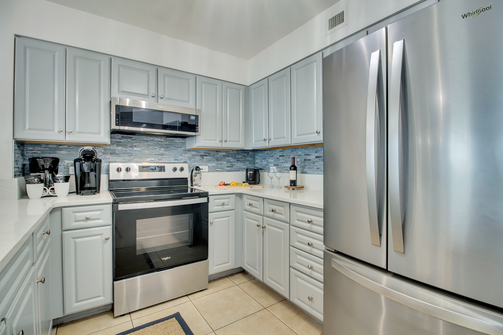 Your fully equipped kitchen features stainless steel appliances and coastal-inspired backsplash, perfect for preparing meals during your stay.