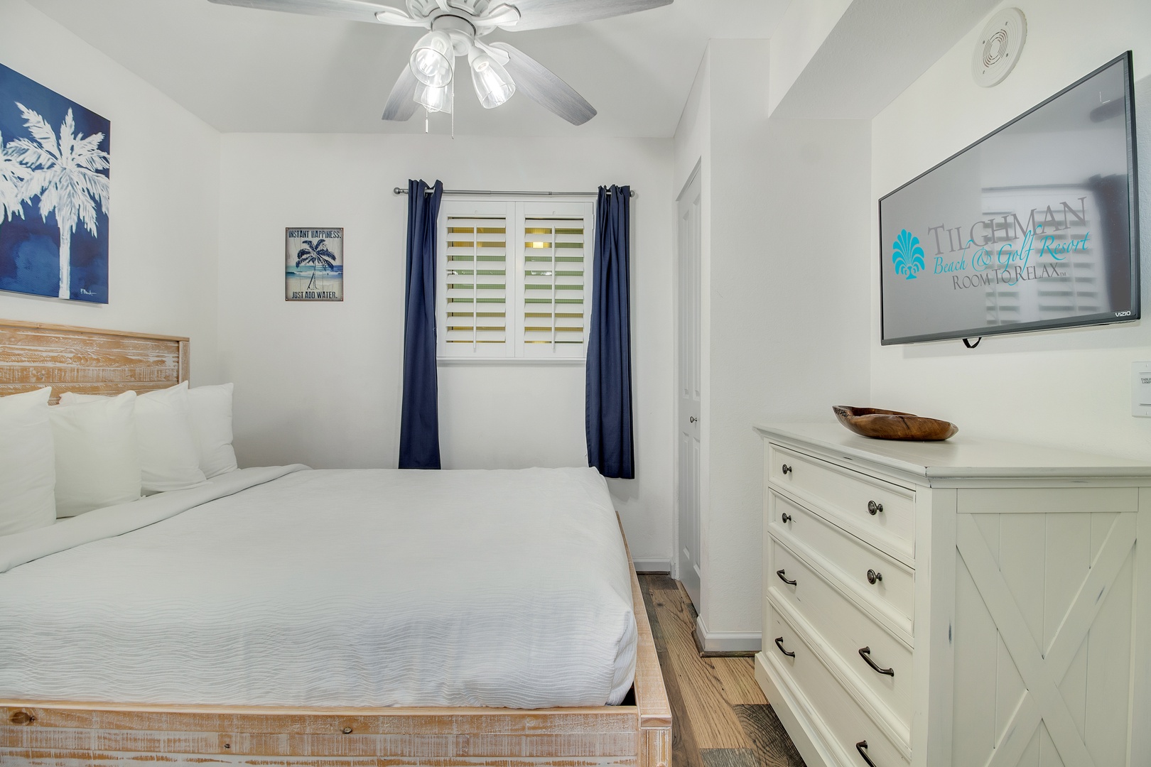 Sink into crisp white linens in your peaceful coastal bedroom, where nautical artwork and warm wood touches create the perfect seaside retreat.