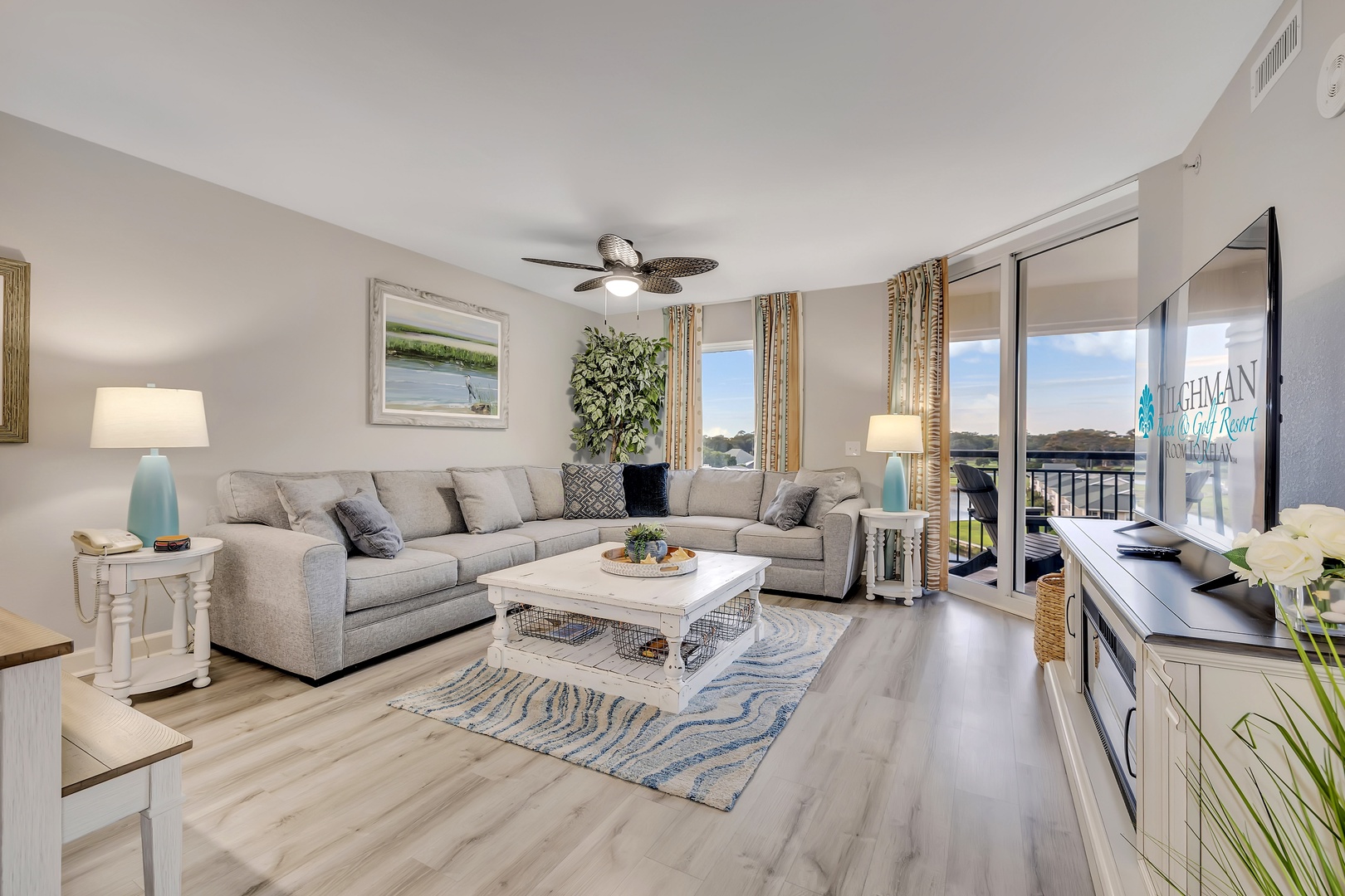 Step into your bright coastal living room, where natural light pours through large windows and a tranquil water view awaits beyond the balcony.