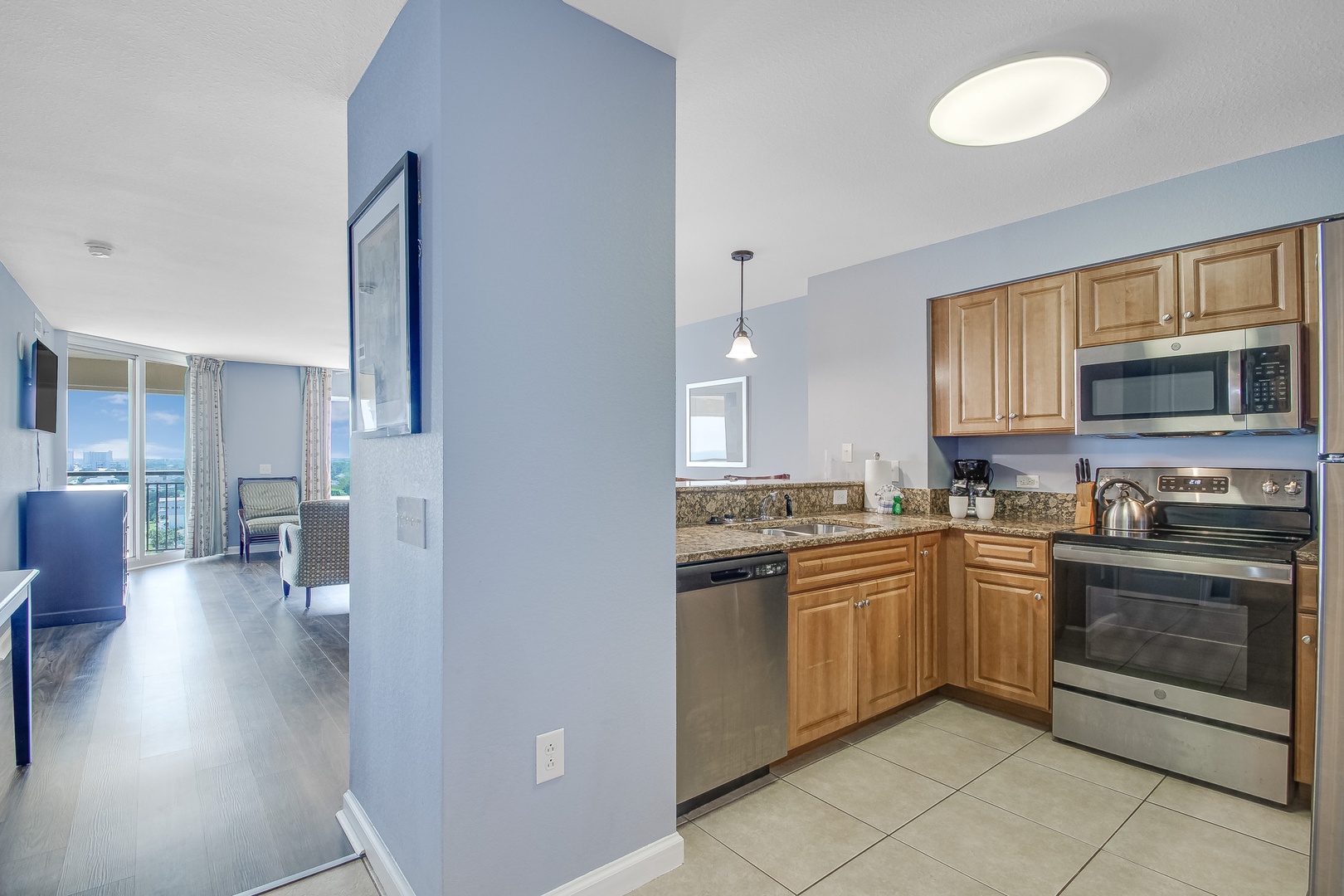 Your fully equipped kitchen features granite counters and stainless steel appliances, flowing seamlessly into your bright living space.