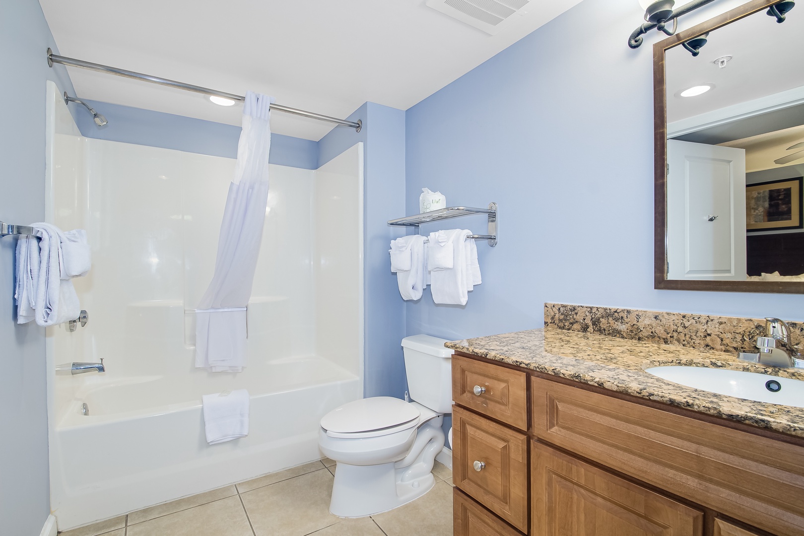 Refresh in your private bathroom featuring granite countertops, spacious shower-tub combo, and calming blue walls that create a spa-like retreat.
