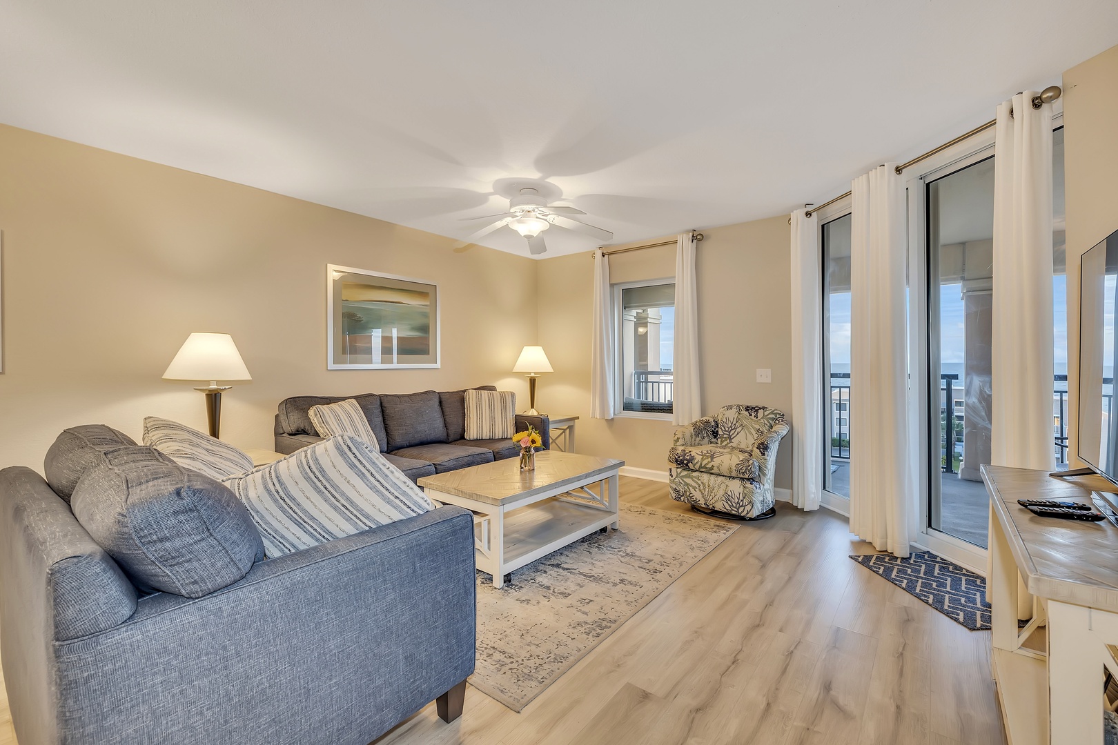 Settle into your inviting living room, where soft natural light and coastal breezes filter through the glass doors. Relax on plush seating and step outside to your private balcony for stunning water views.