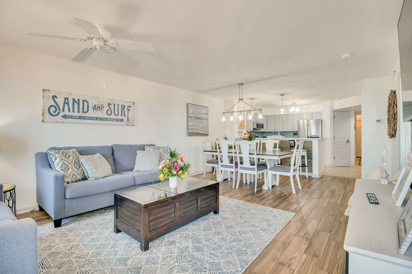 Relax in your bright, coastal-themed living space where beach-inspired decor and comfortable seating create the perfect vacation atmosphere.