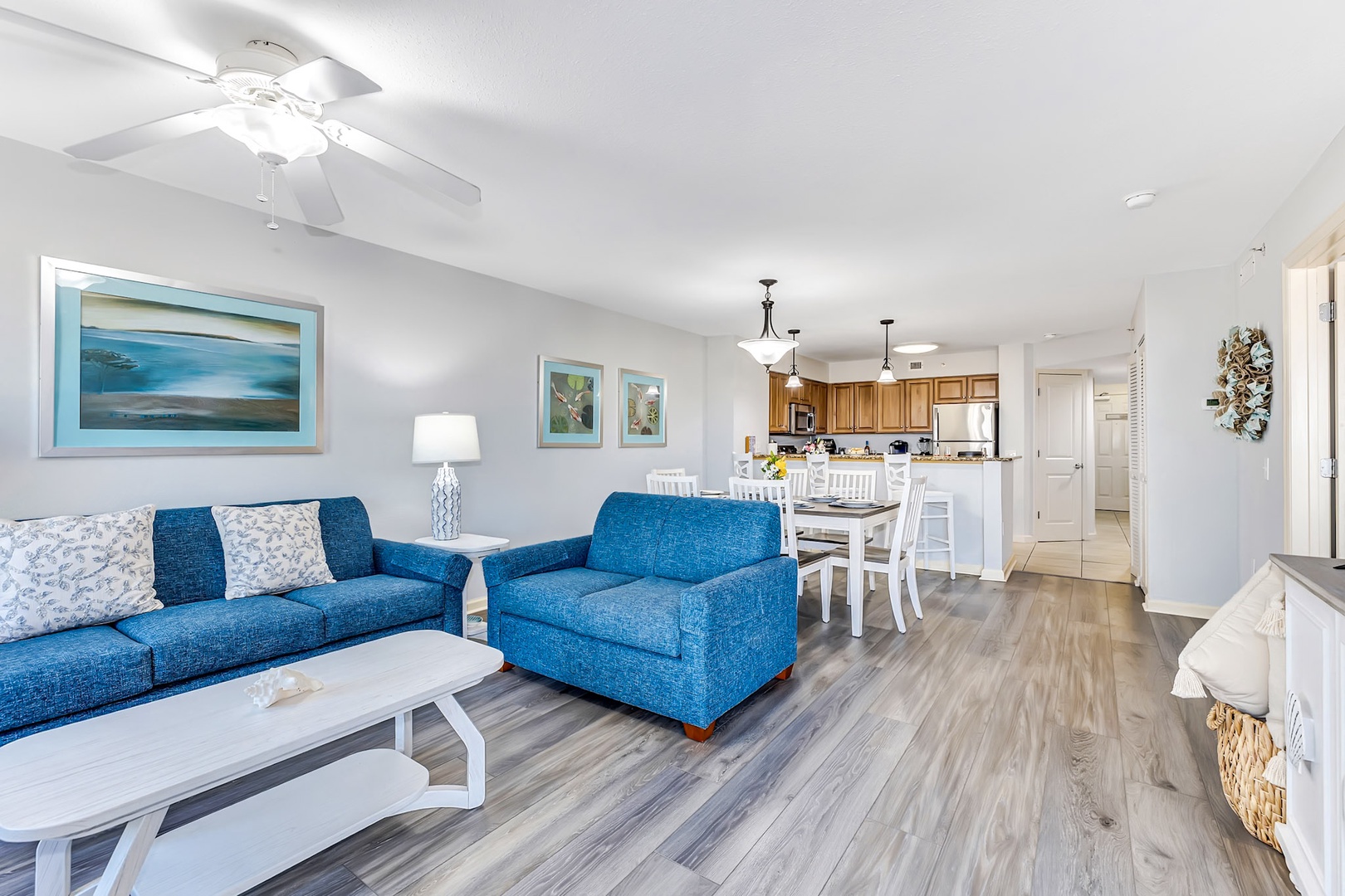 Unwind in your bright, open living space with cozy seating, coastal touches, and everything flowing seamlessly into the fully equipped kitchen—perfect for lazy mornings or lively evenings together.