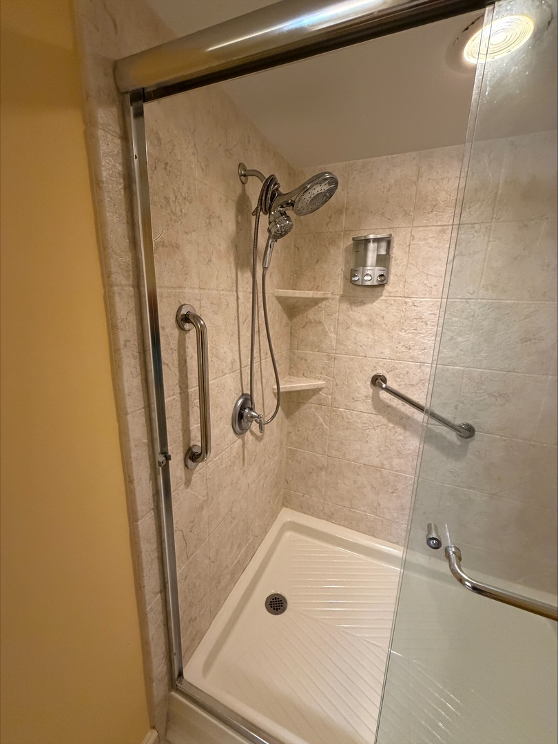Step into your spacious walk-in shower with dual showerheads and convenient grab bars for safety. The built-in corner shelves keep your essentials within easy reach.
