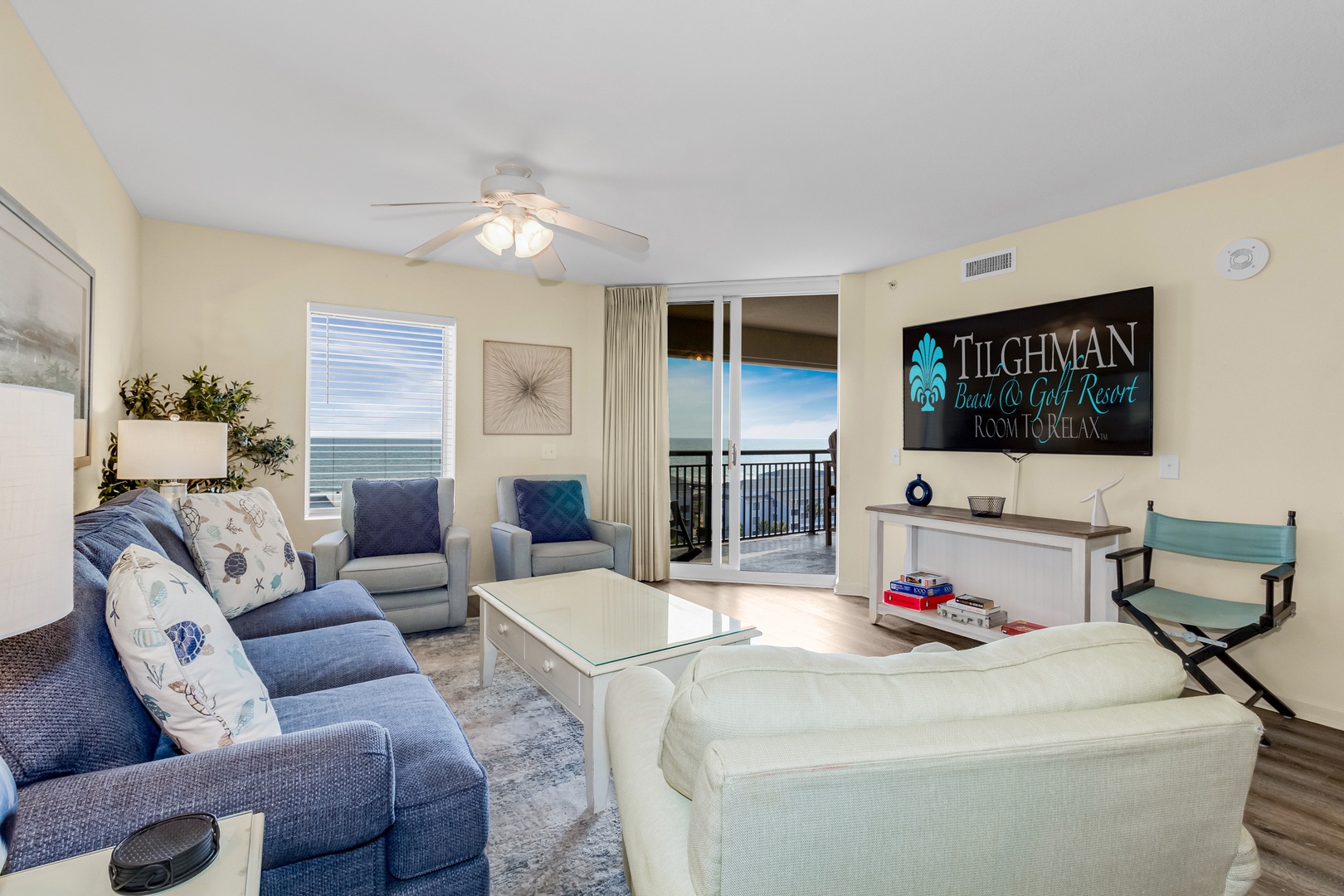 Sink into comfortable seating while ocean breezes flow through your balcony doors in this bright, coastal-themed living space.