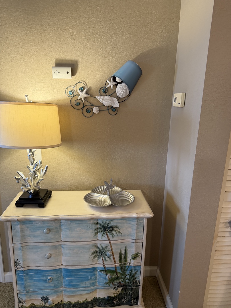 Your peaceful bedroom sanctuary features a comfortable bed with tropical-themed bedding and nautical wall art that creates a serene coastal atmosphere.